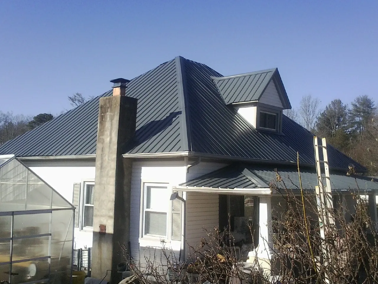 Dark blue standing seam metal roof on a white farmhouse with dormer — Slate & Tile Roof Repair by Roofing Brothers in Greenbank