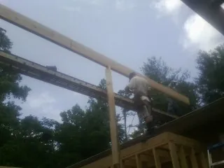 Carpenter setting a ridge beam over a new addition frame — Ice Dam Removal by Roofing Brothers in Greenbank