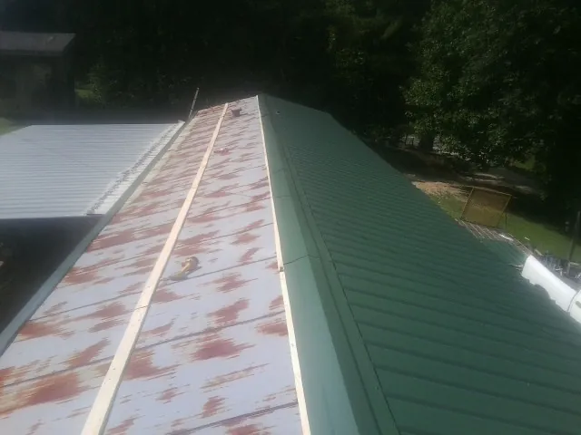Old rusted panels beside newly installed green metal roofing — Wind Damage Roof Repair by Roofing Brothers in Greenbank