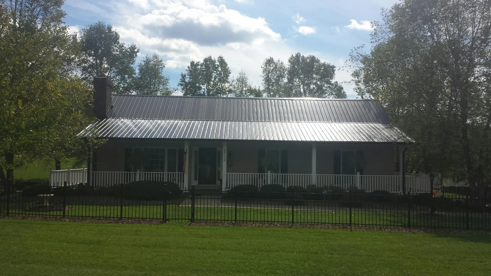 Gray metal roof on a brick ranch with a full width front porch — Gutter Guard Installation work by our crew in Greenbank