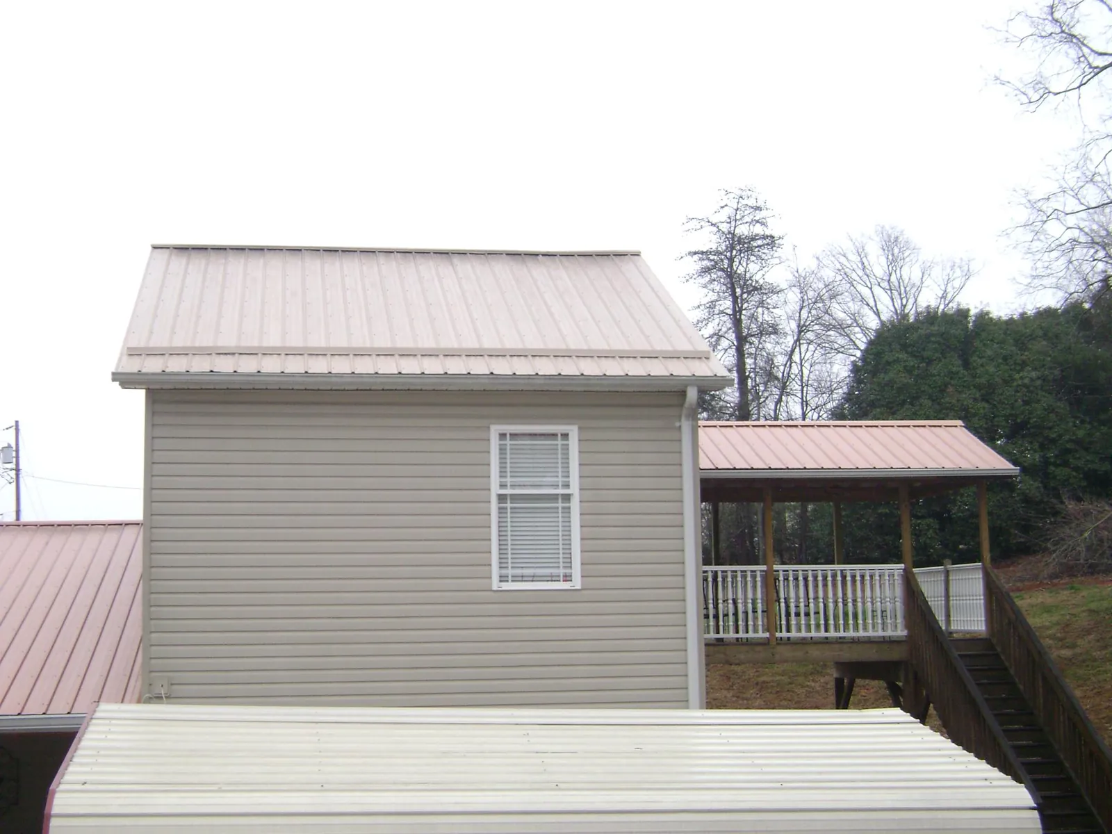 Tan metal roofs on a two story addition and attached porch, from a Roof Replacement job in Greenbank