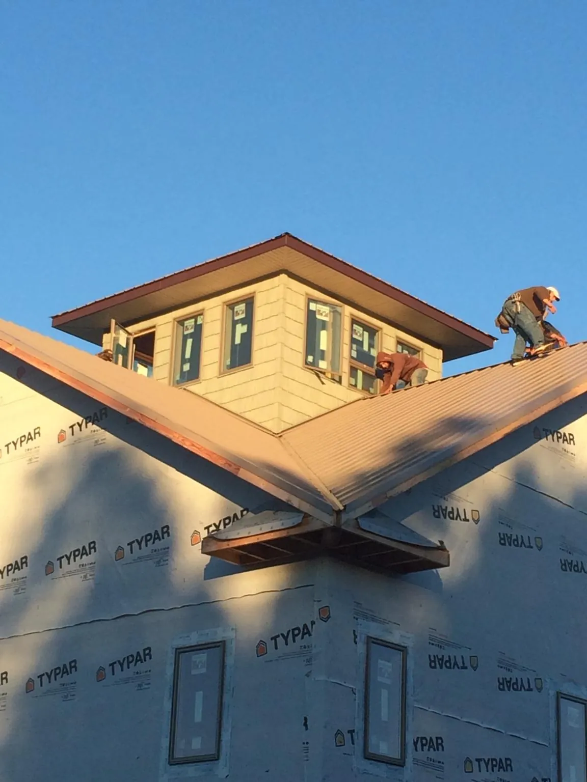 Roofers working around a rooftop cupola on a new metal roof at sunset — Roof Waterproofing in Greenbank by Roofing Brothers